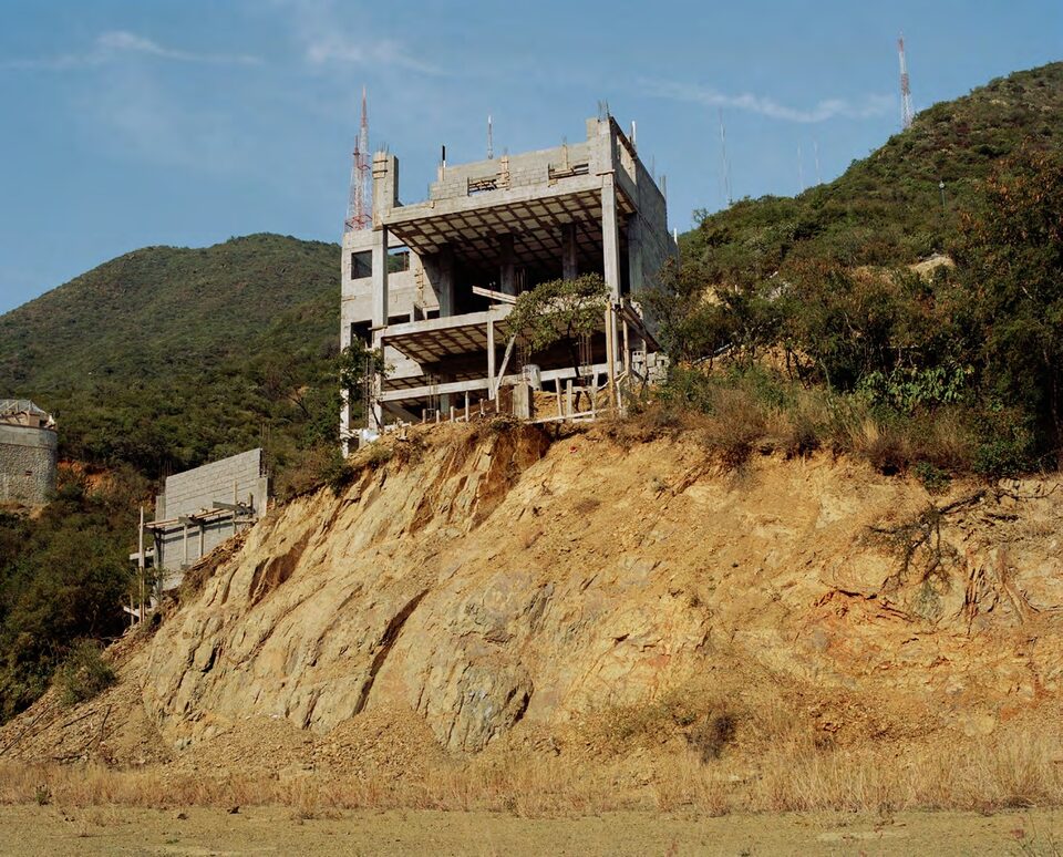 Unfinished concrete building on a rocky hillside with radio antennas